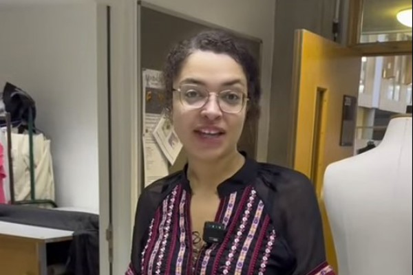 HNC costume design student presenting their work in a classroom, with sewing patterns and fabric samples on the table.