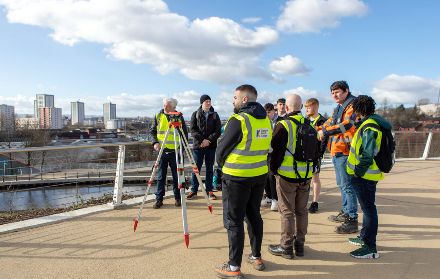 Civil engineering students using surveying equipment during an outdoor fieldwork session overlooking Glasgow.