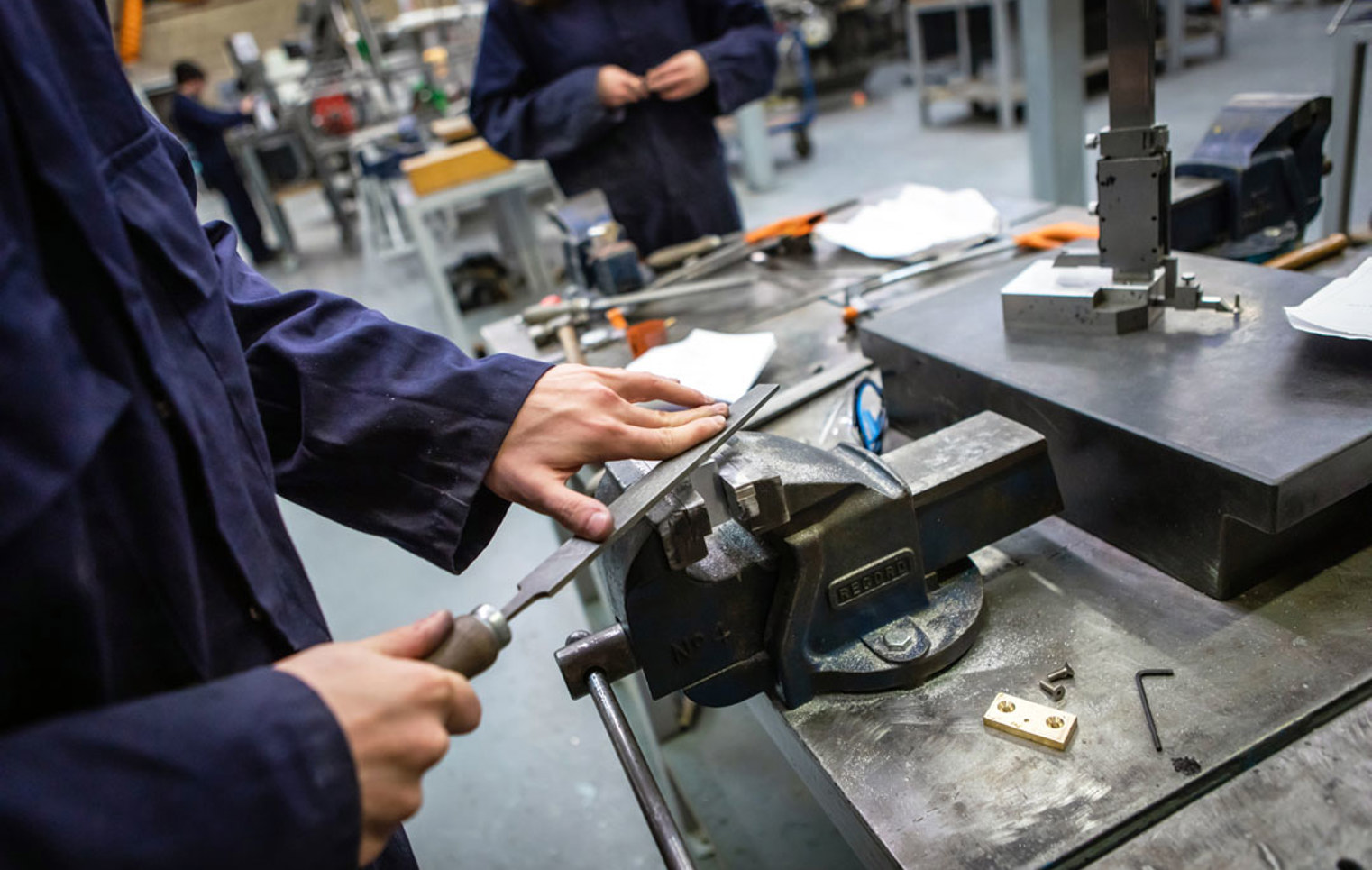 Student filing metal secured in a vice during a hands-on engineering task.