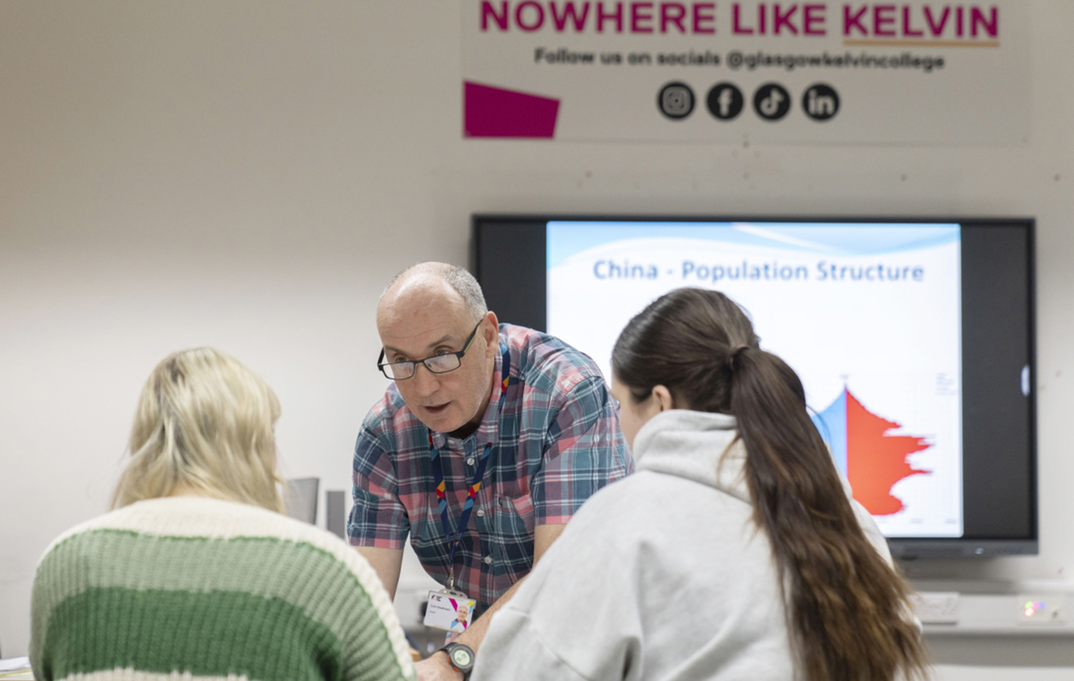 Friendly one-to-one teaching moment between lecturer and students at Glasgow Kelvin College.