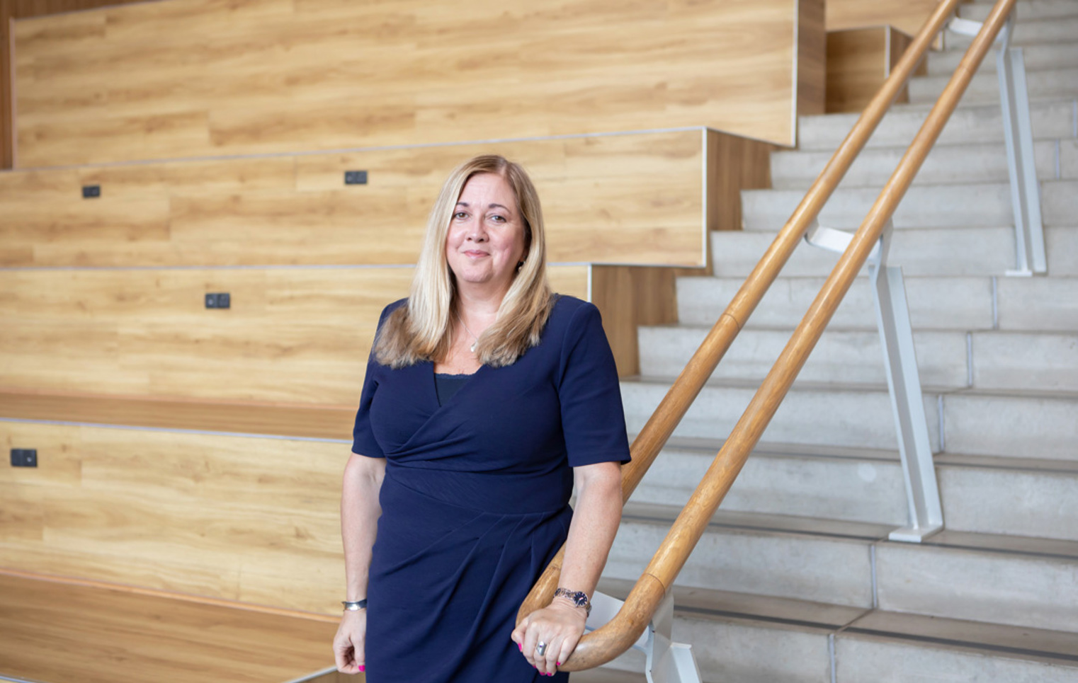 Jeanette Evans, Vice Principal of Operations at Glasgow Kelvin College, standing beside a staircase in the college’s modern lecture space