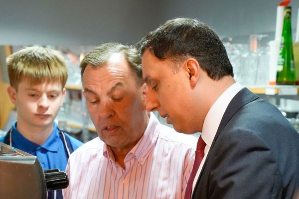Anas Sarwar observing coffee-making skills with hospitality students in barista training session.