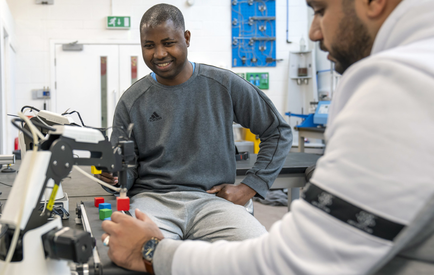 Students working with a robotic arm system during a practical electronics engineering session.