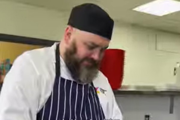Chef at Glasgow Kelvin College preparing a plant-based dish during a Forward Food workshop, mixing ingredients in a stainless steel bowl