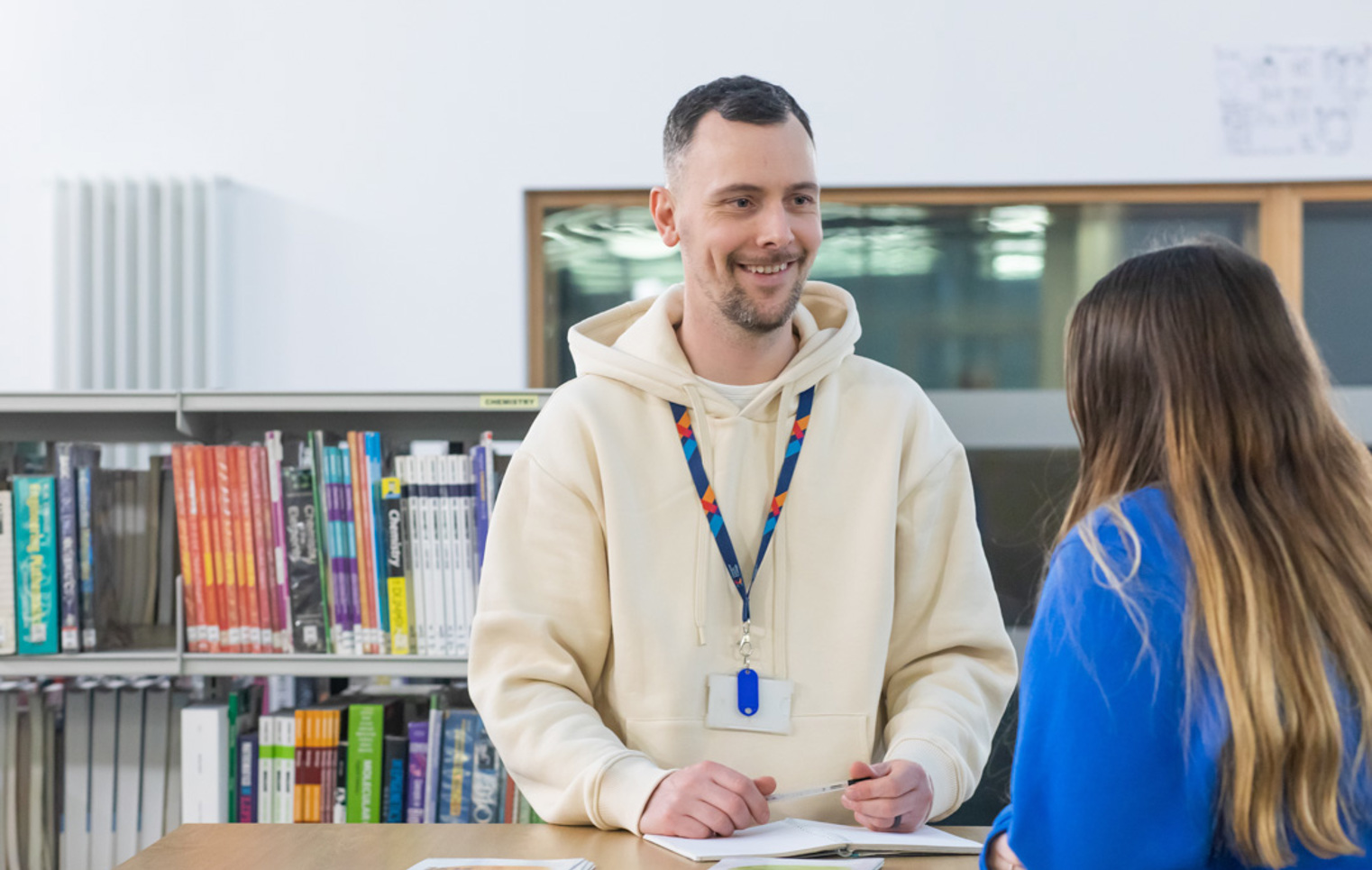 Student receiving support from a staff advisor at a desk in the Glasgow Kelvin College library.
