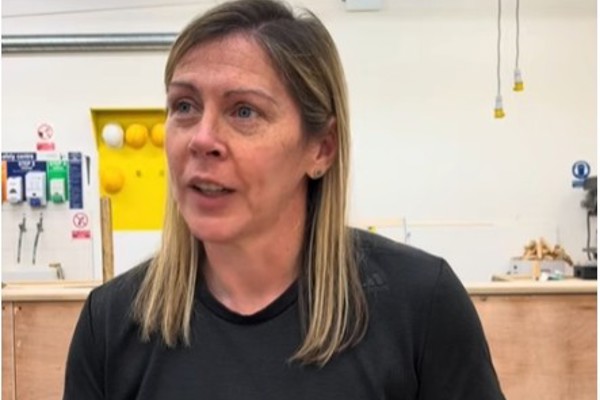 A female joinery lecturer in a black t-shirt speaking in a well-equipped workshop at Glasgow Kelvin College, with the text 'Why study joinery at Kelvin?' displayed above her.