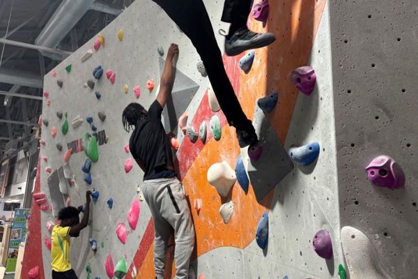 Student climbing an indoor bouldering wall at the Climbing Academy in Glasgow.