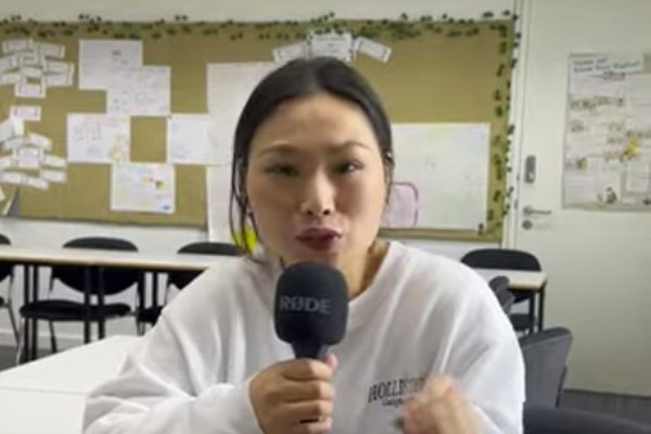 Tingting, a former Childcare with ESOL student at Glasgow Kelvin College, sits in a classroom holding a microphone and sharing her experience on the course.