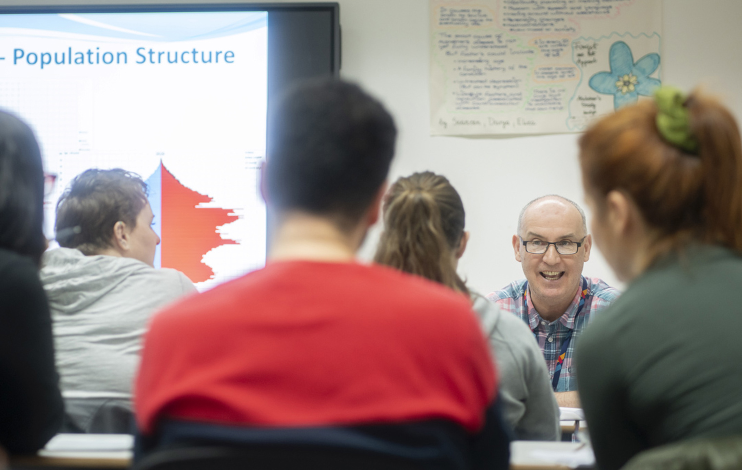 Lecturer smiling while teaching population structure in a lively classroom discussion.