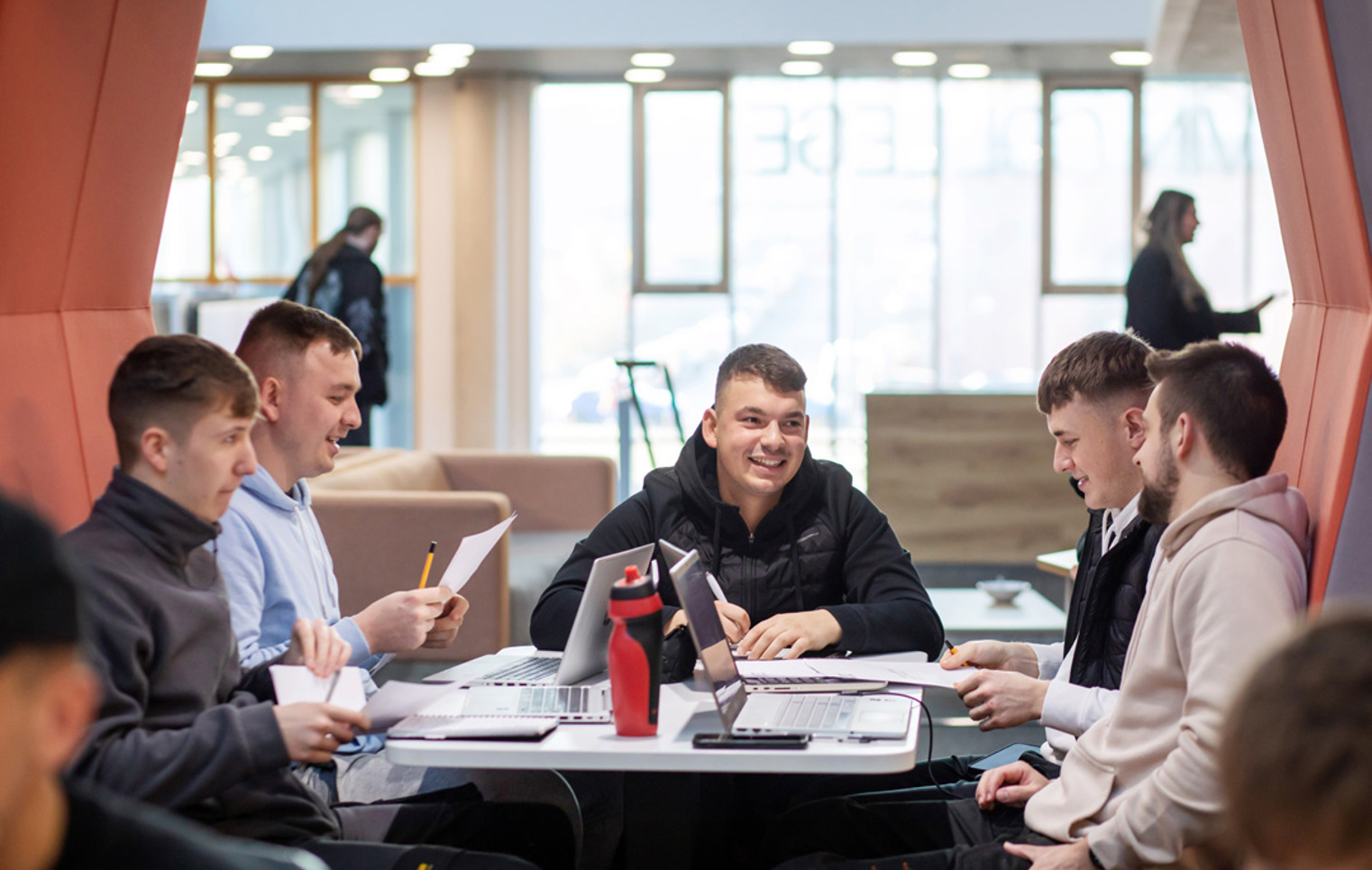 Group of male students working together on laptops and worksheets in a modern study pod at Glasgow Kelvin College Springburn campus