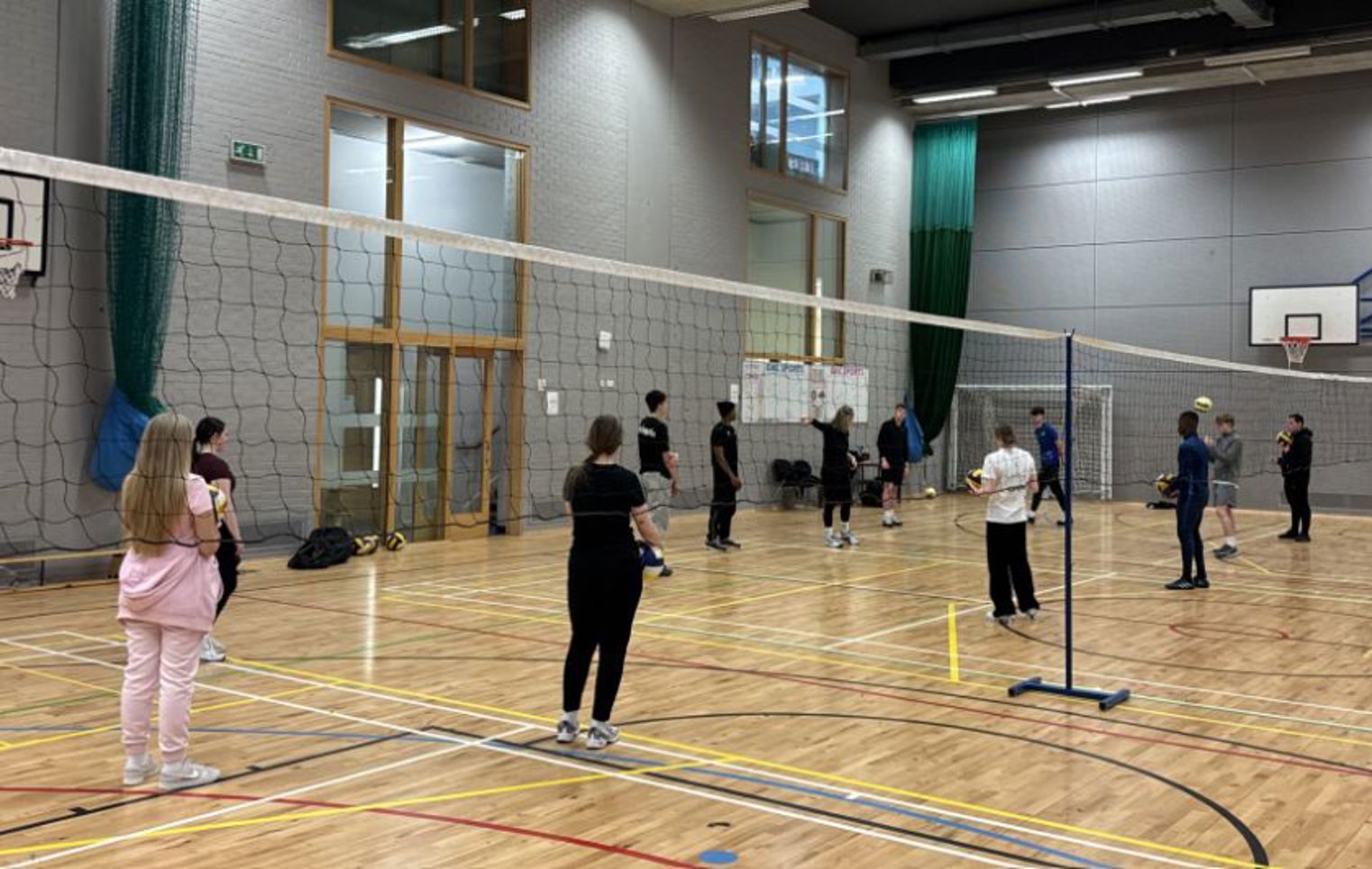 Students taking part in a volleyball training session in the college sports hall during a Scottish Volleyball CPD event.