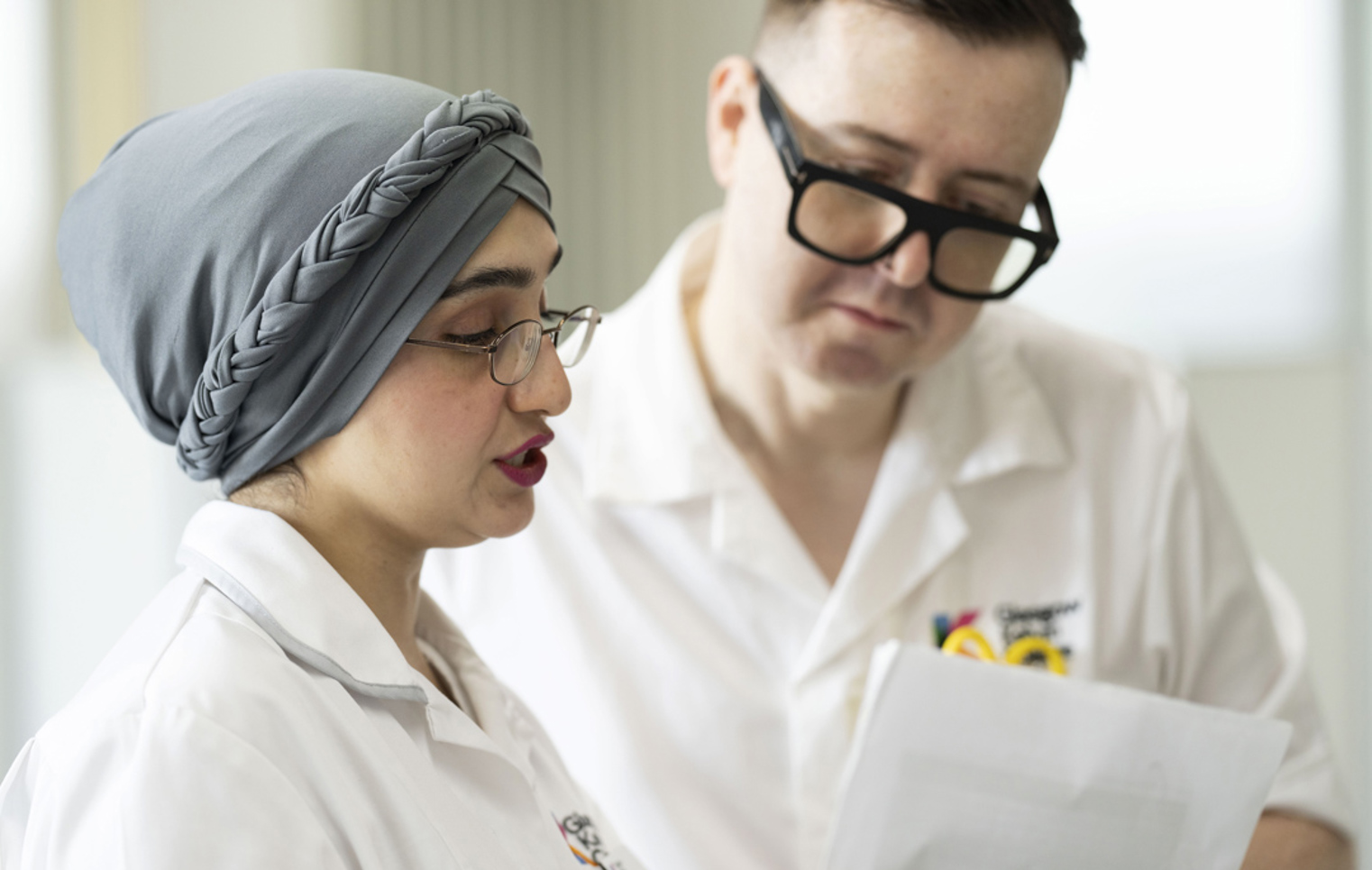 Close-up of two healthcare students reviewing patient notes in a practical classroom setting.