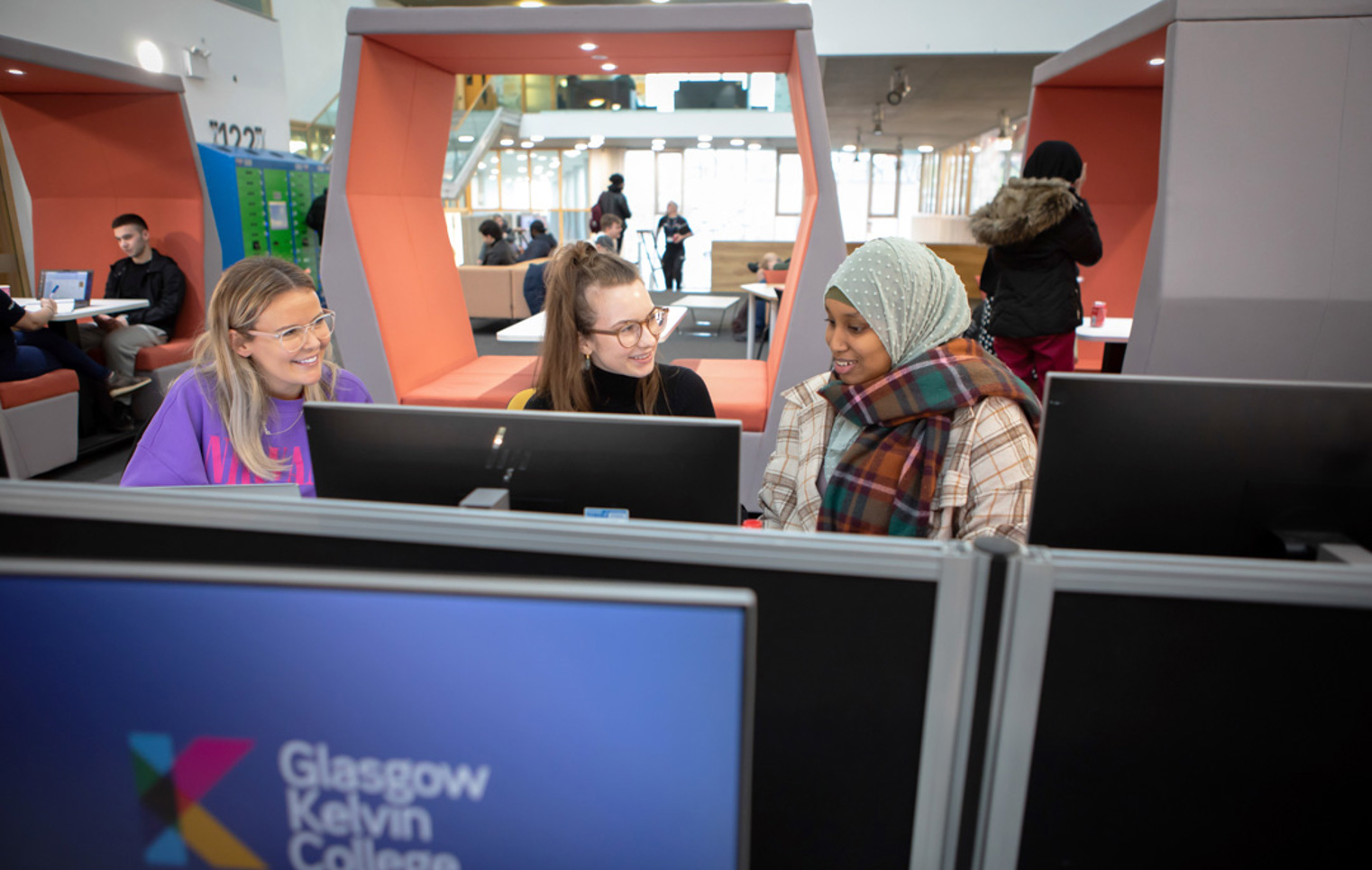 Three students using desktop computers and working together in the Springburn campus library at Glasgow Kelvin College