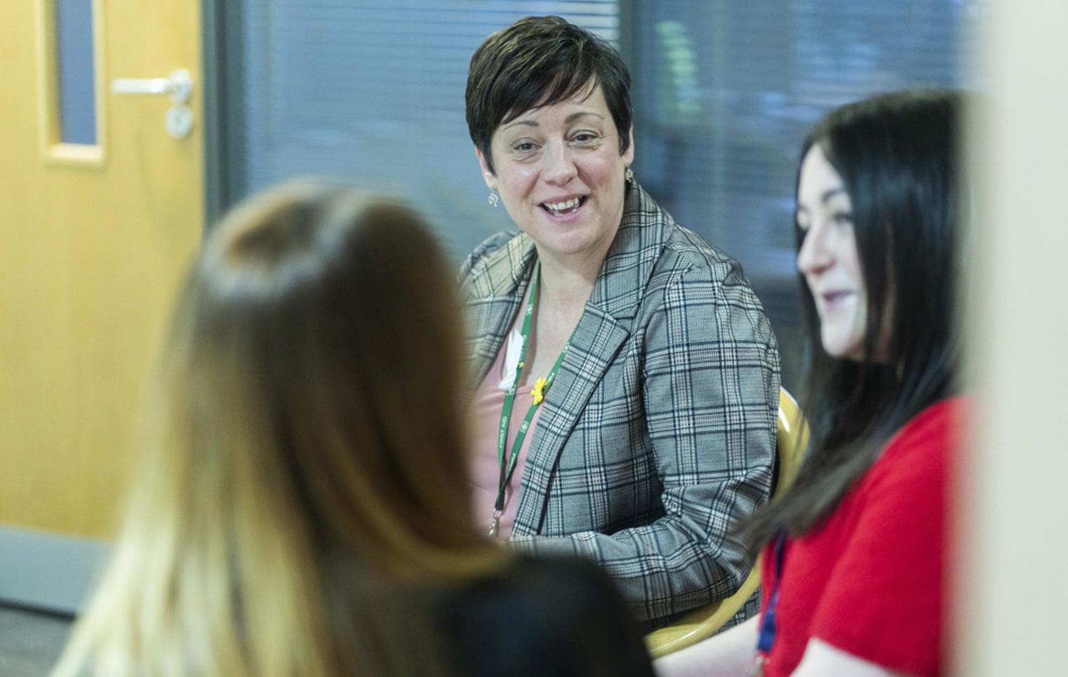 Glasgow Kelvin College staff member in conversation with two colleagues during an informal meeting in an office setting
