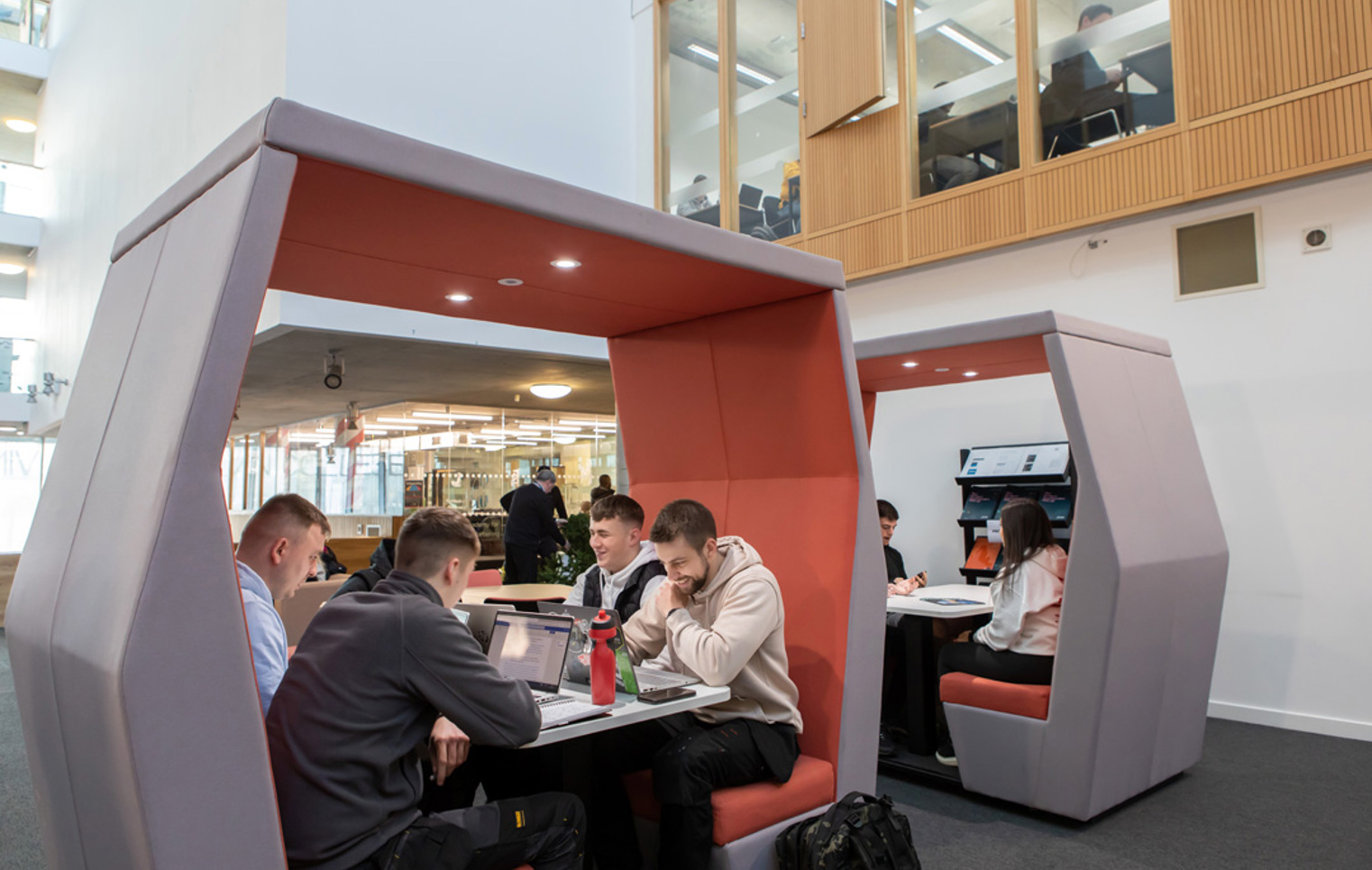 Students working together in modern study pods at Glasgow Kelvin College’s Springburn campus, using laptops and notebooks in a collaborative space.