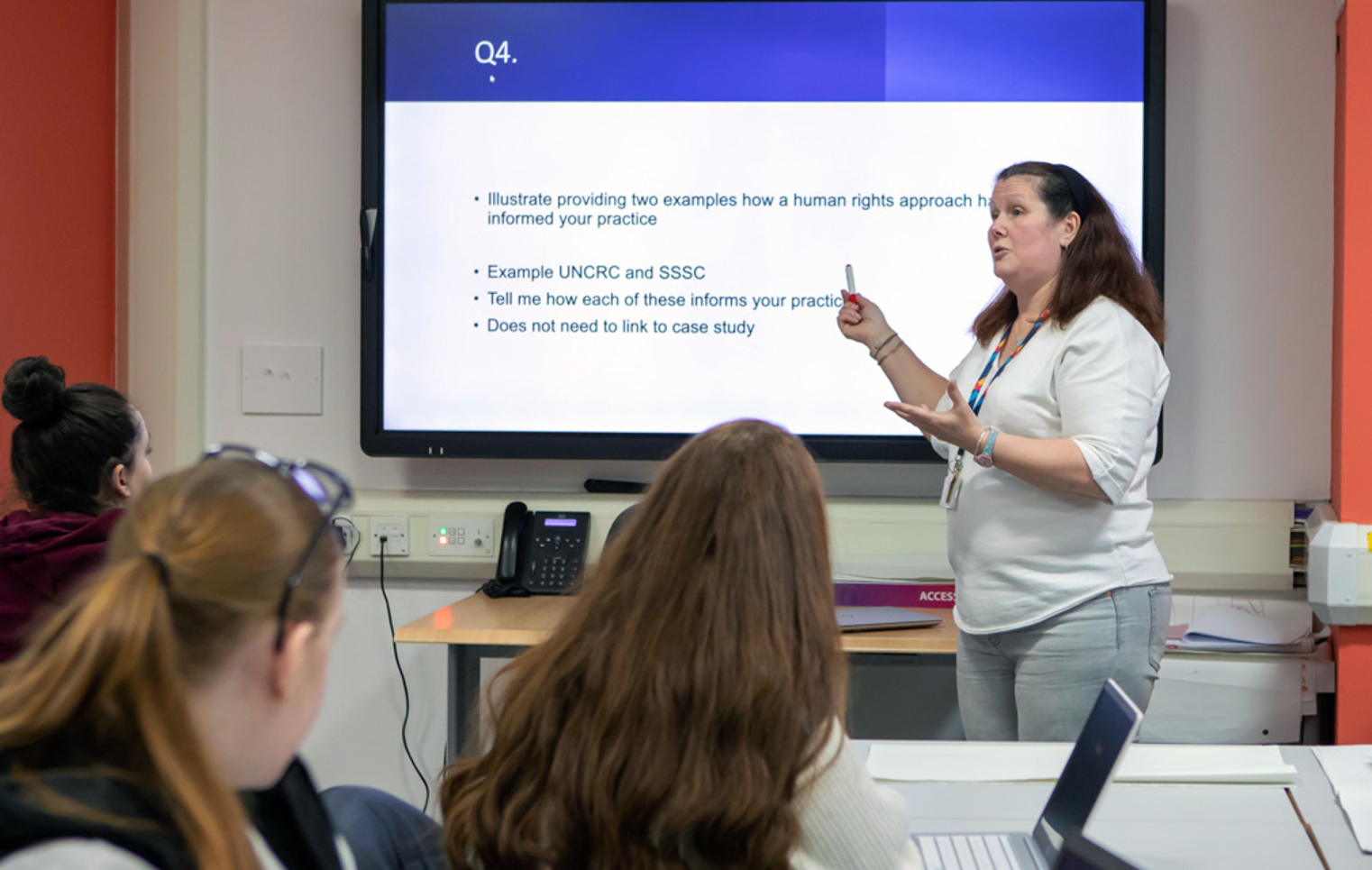 A lecturer at Glasgow Kelvin College leading an engaging discussion with students, exploring human rights approaches in practice.