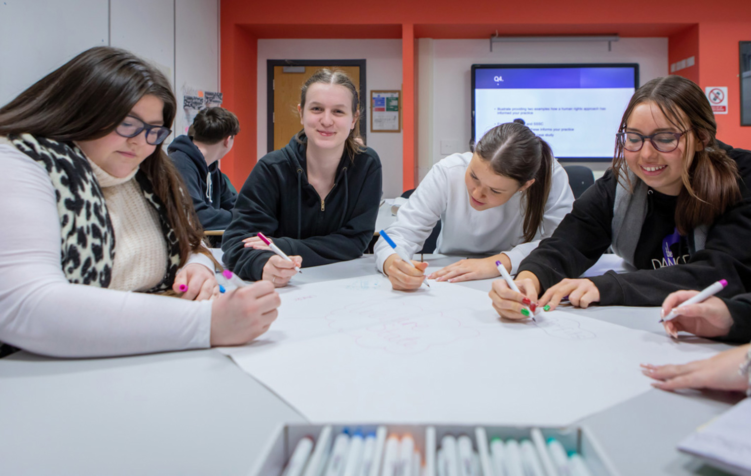 A vibrant snapshot of Glasgow Kelvin College students working together, sharing thoughts and smiles in a supportive classroom setting.