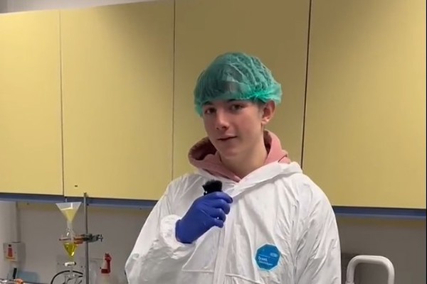 Science student Robert wearing protective clothing and speaking into a microphone in a college laboratory.