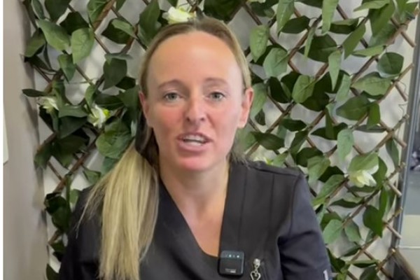A beauty student in a black uniform sharing their journey into the beauty industry, seated in front of a green floral backdrop.