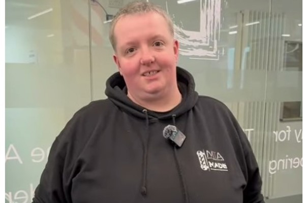 A barbering student in a black hoodie discussing skin fades and short back and sides in a training facility.
