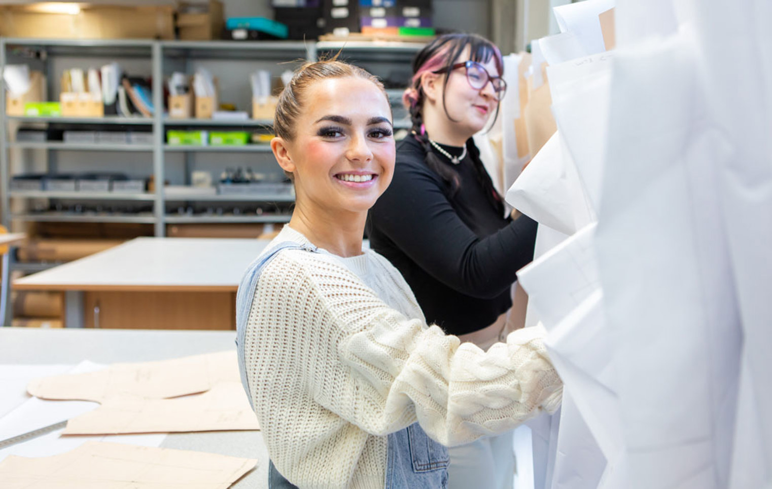 Two fashion students organizing and selecting design patterns in a creative workspace.