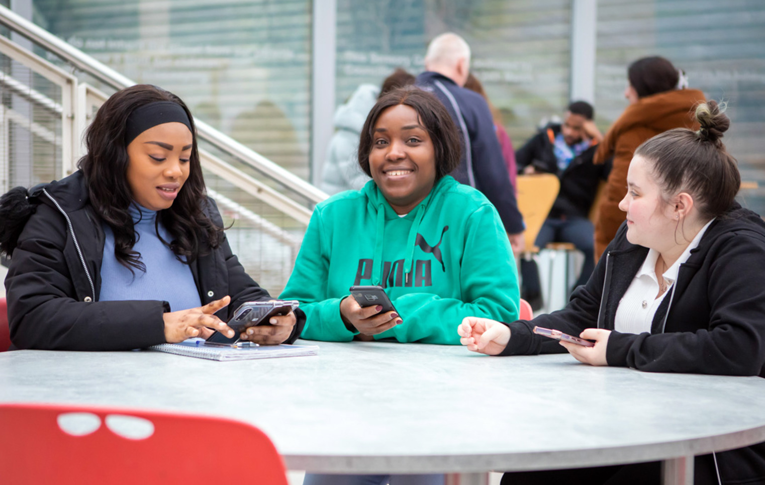 Student sitting in a communal area at Glasgow Kelvin College’s East End Campus, working or relaxing in a modern, shared space.