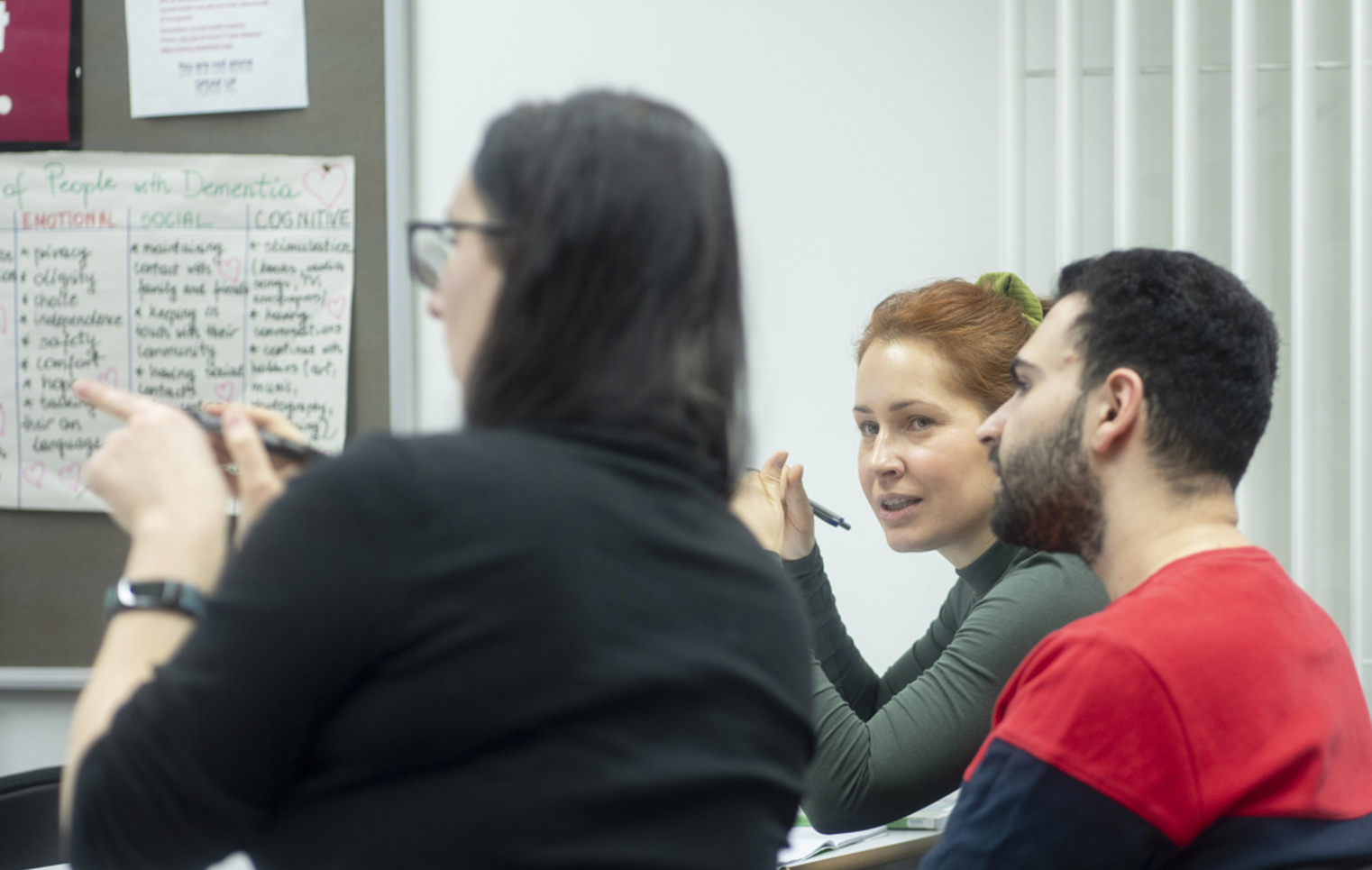 Students actively take part in a humanities class, discussing emotional and cognitive needs of people with dementia.