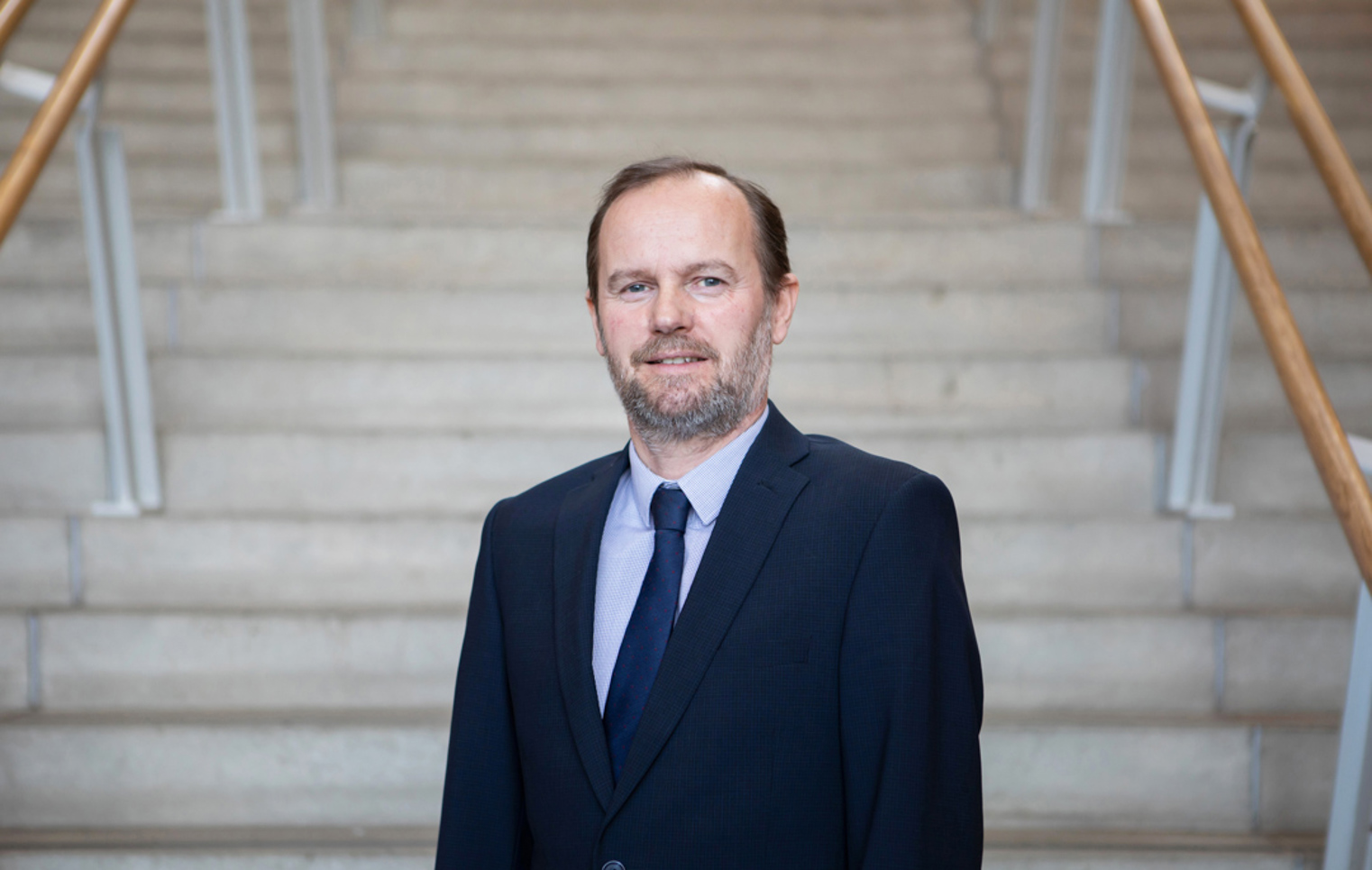 Robin Ashton, Vice Principal of Curriculum and Quality Enhancement at Glasgow Kelvin College, standing on an internal staircase in formal attire