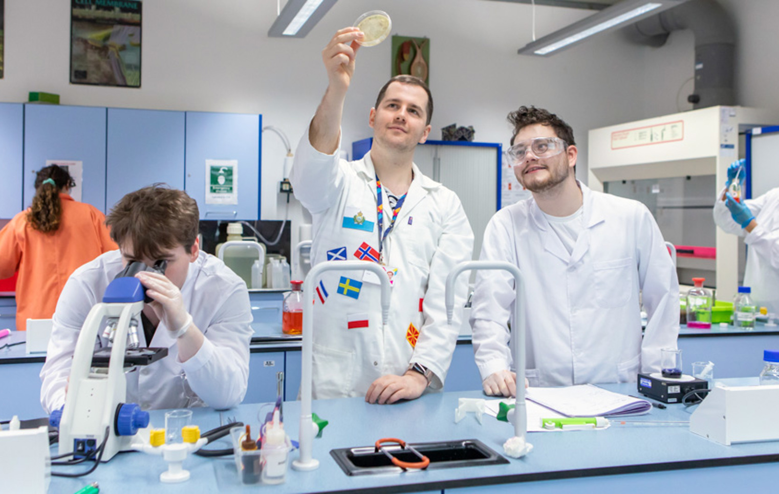 Science students and lecturer analysing samples with microscope and petri dish at Glasgow Kelvin College
