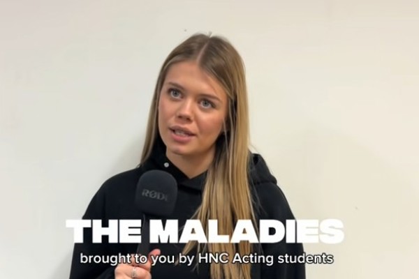 HNC Acting student speaking into a microphone while promoting “The Maladies” performance at Glasgow Kelvin College.