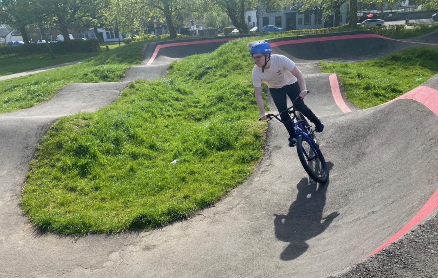 Student riding a BMX bike on an outdoor pump track during a sunny day, part of the Pathways to Employment Skills programme.