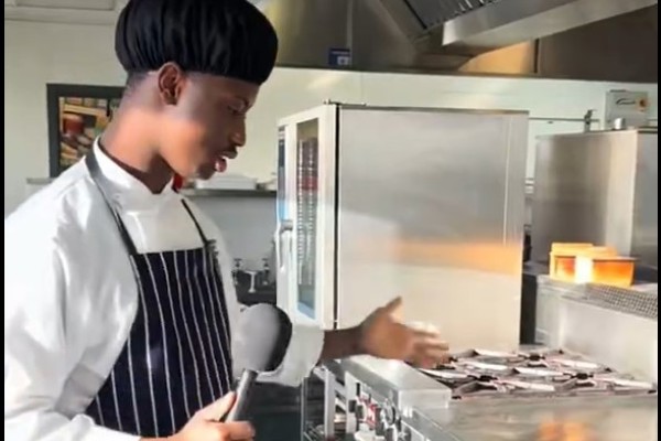 Hospitality student Mohammad giving a tour of the college training kitchen, demonstrating equipment during an interview.