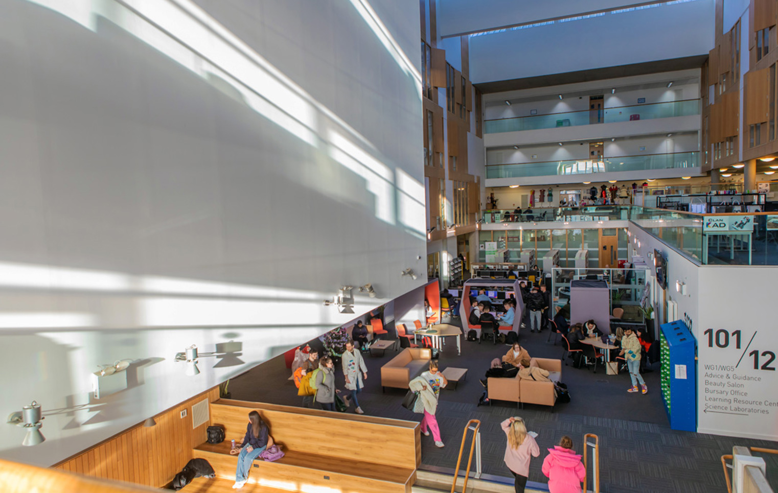 Bright, multi-level interior of Glasgow Kelvin College’s Springburn Campus, showing students studying and socialising in the central communal and library area.