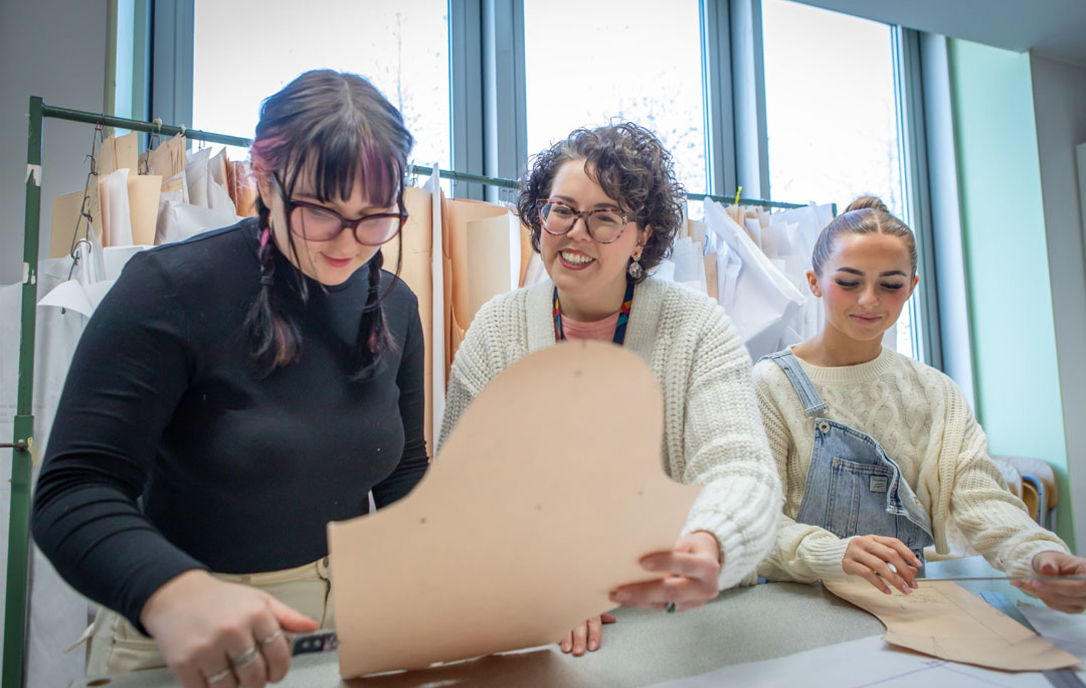 Fashion students collaborating on a sewing project under the guidance of their lecturer.